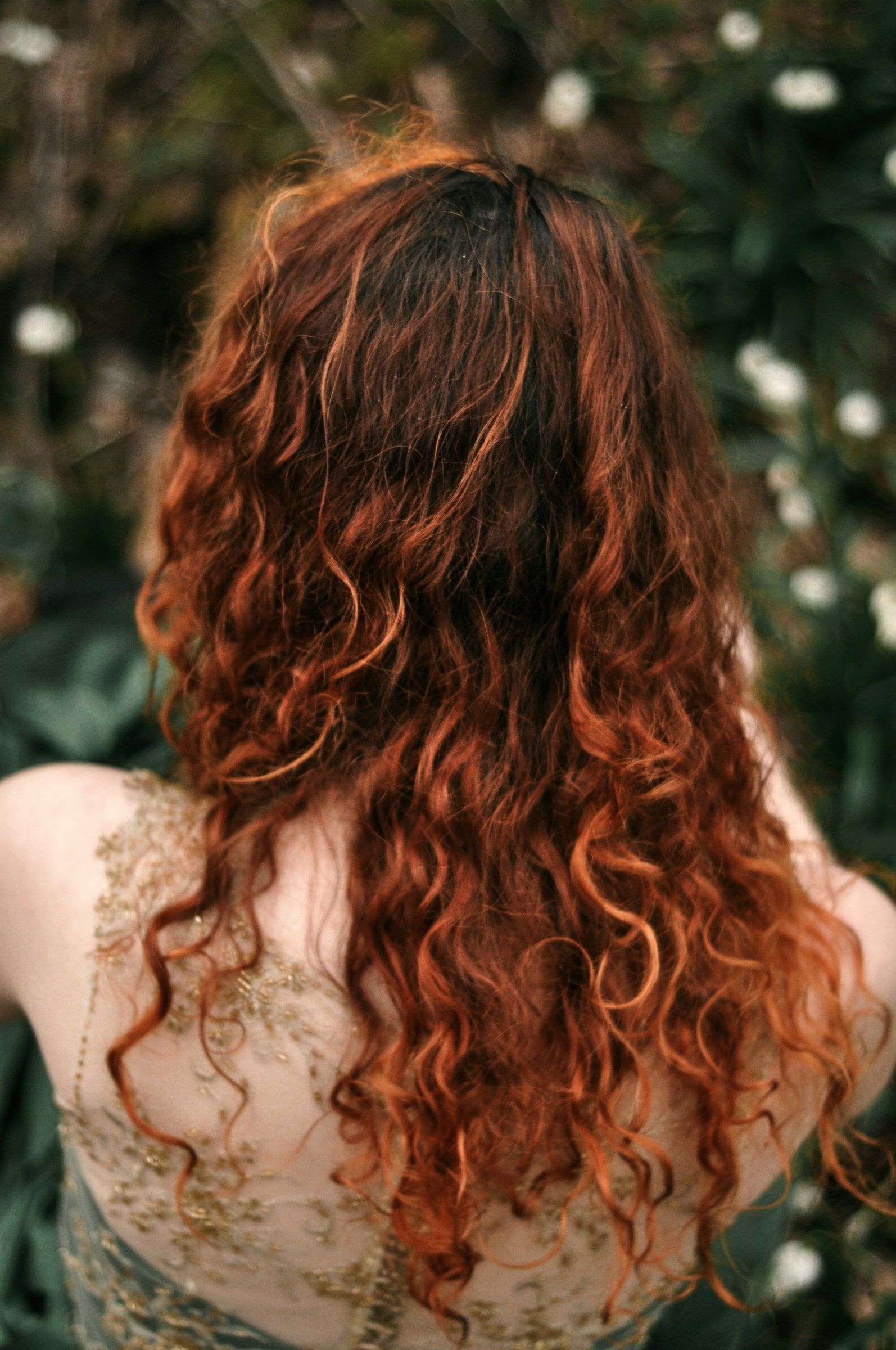 Langes, glänzendes Haar in Kupfer mit lockeren Locken, von hinten